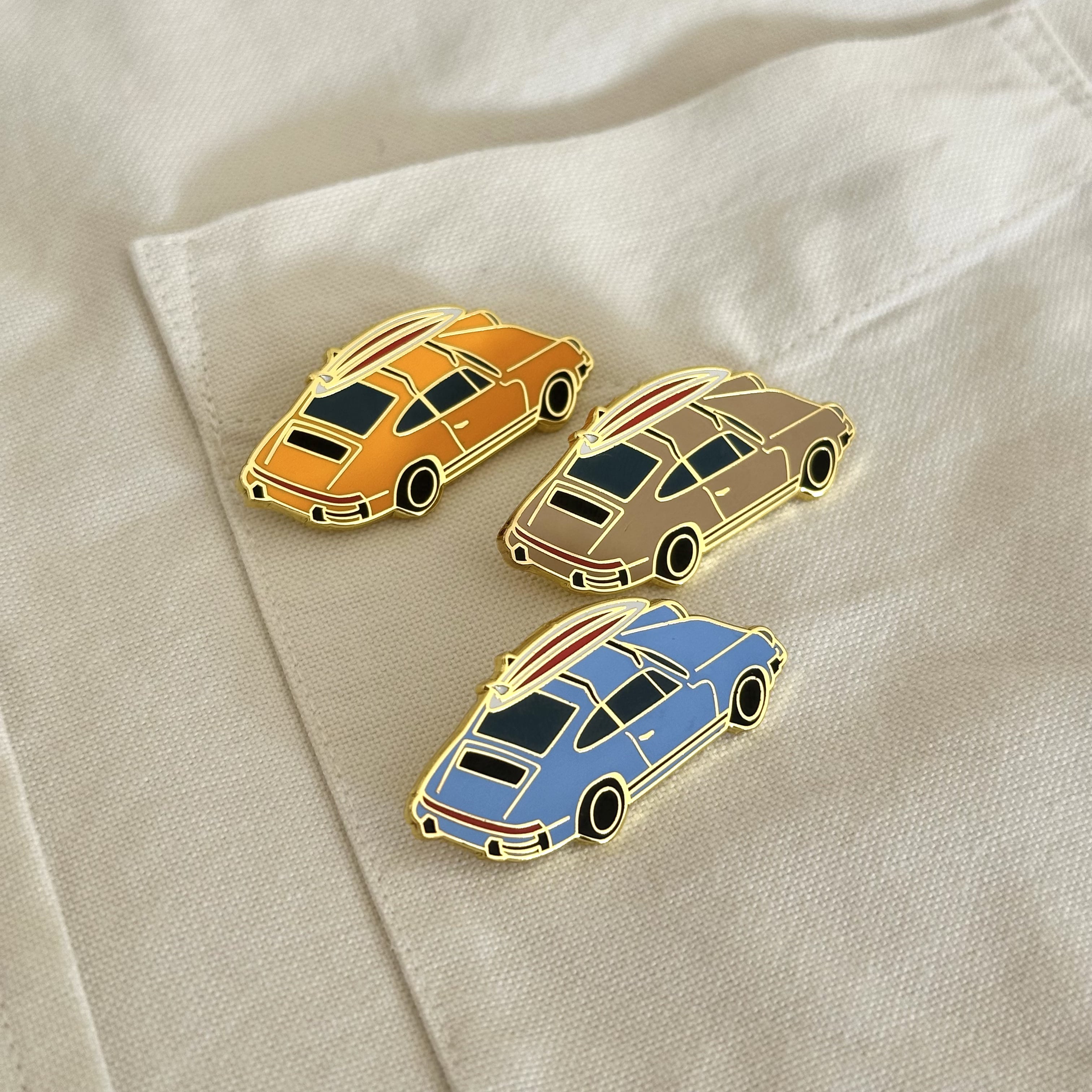 rennbetrieb enamel pin of a porsche 911 g model with a surfboard on the roof