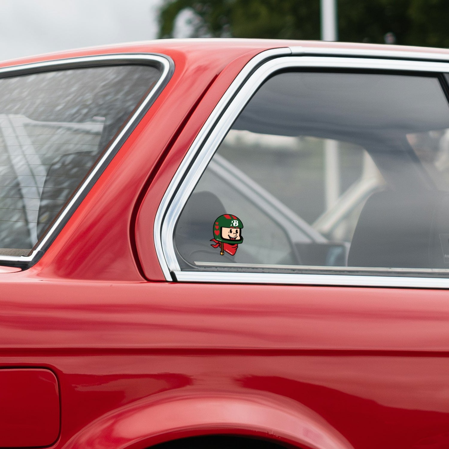 rennbetrieb mascot helmut with green helmet and a red scarf on a red car