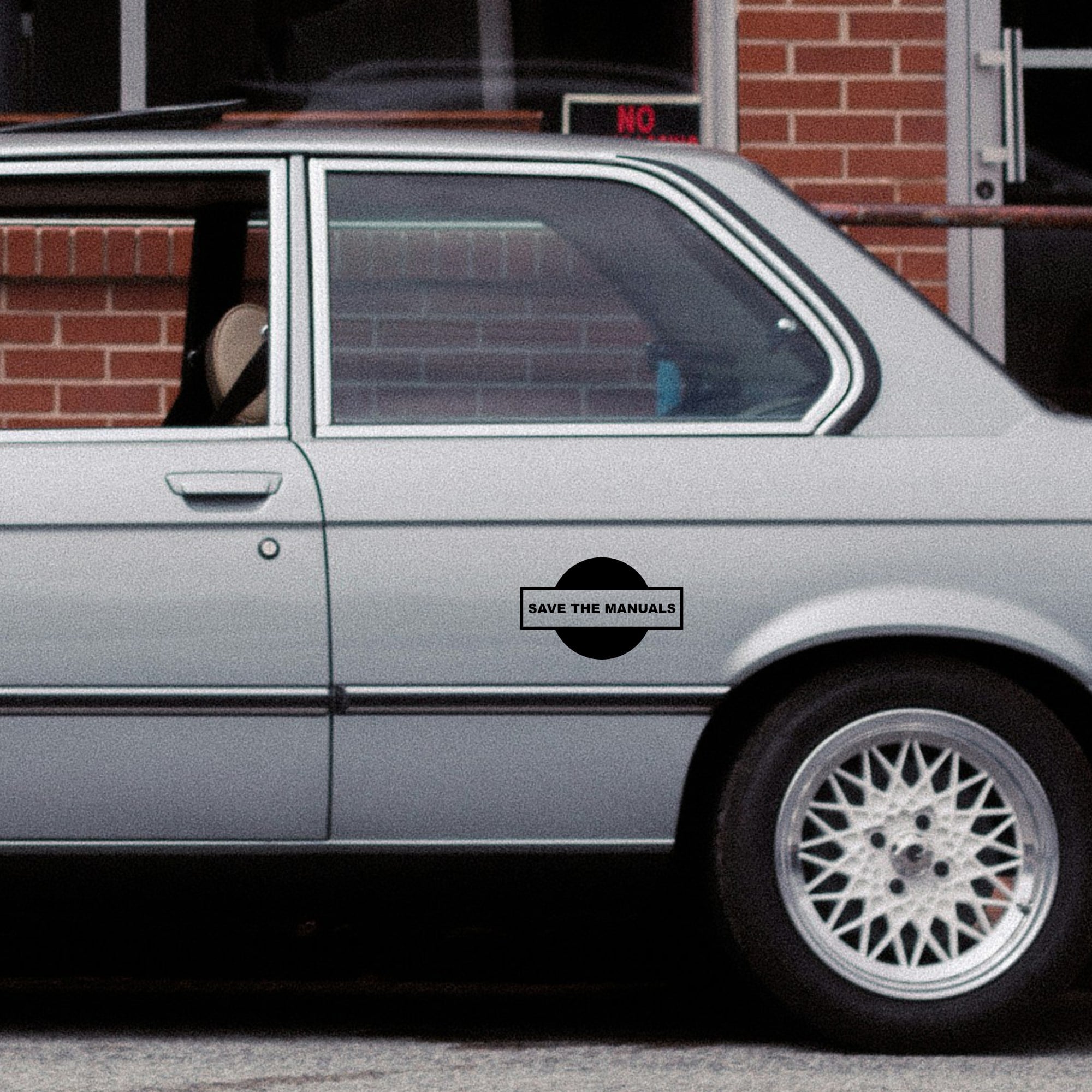 SAVE THE MANUALS STICKER on silver bmw car