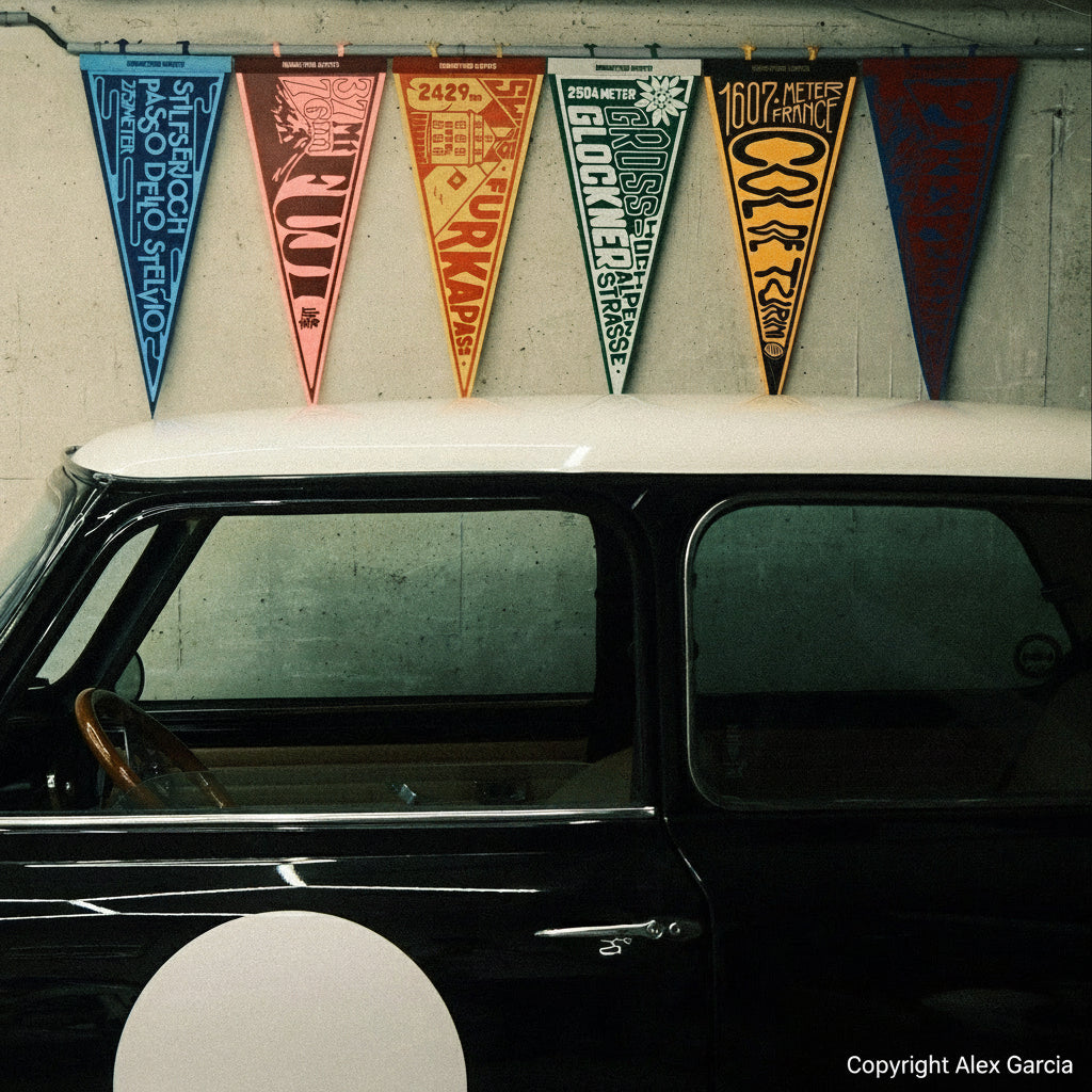 Vintage car with colorful pennants hanging above it on a wall.
