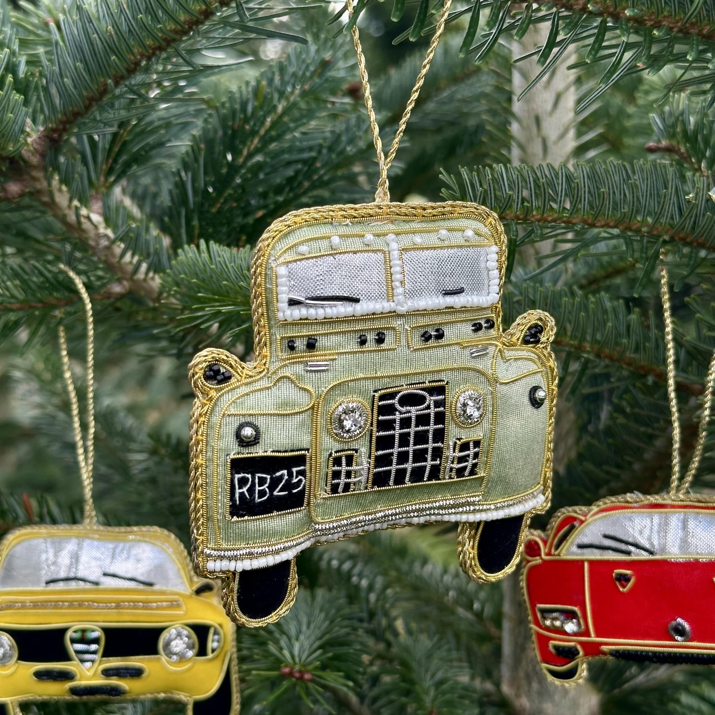 Decorative car ornaments hanging on a Christmas tree.