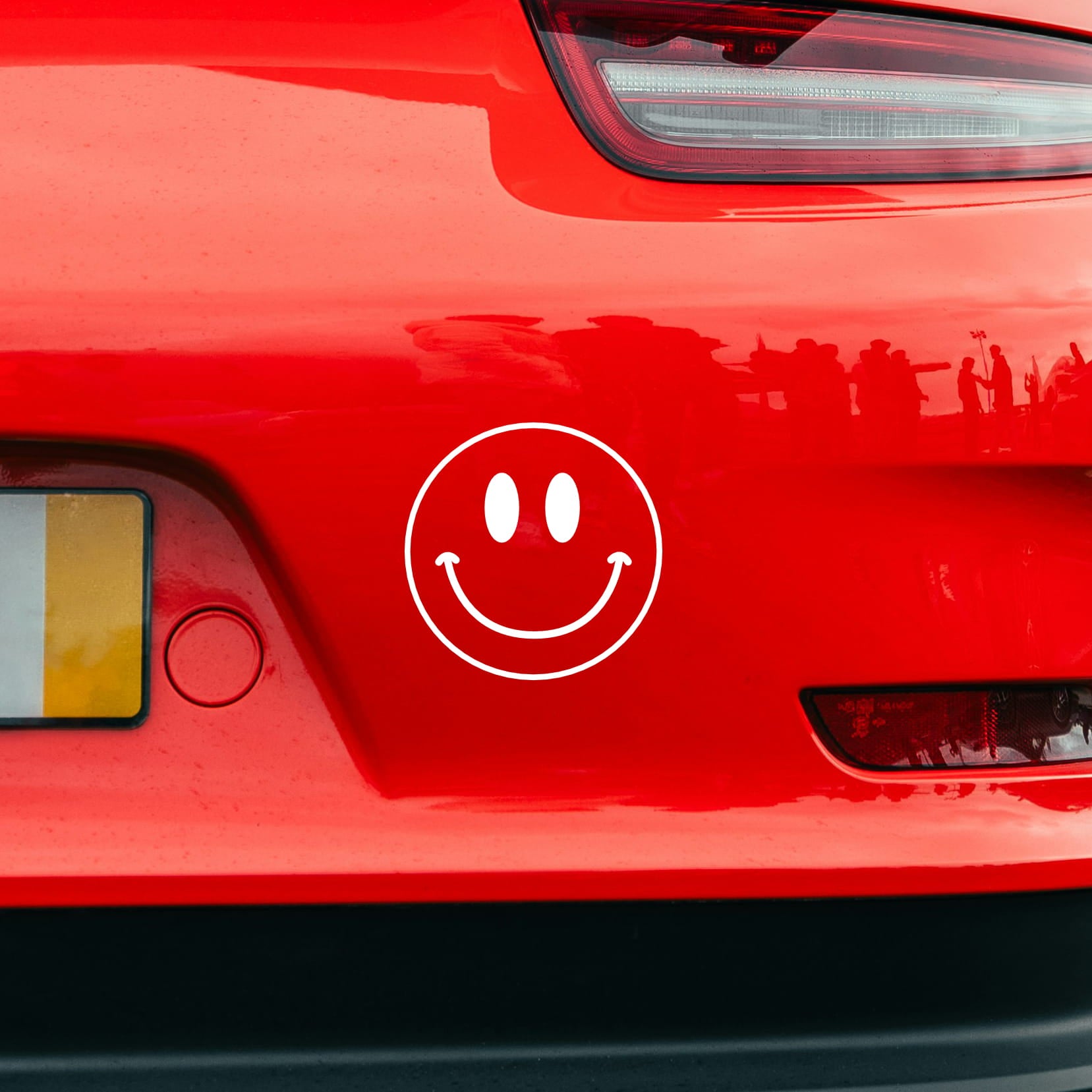 smiley sticker on red porsche
